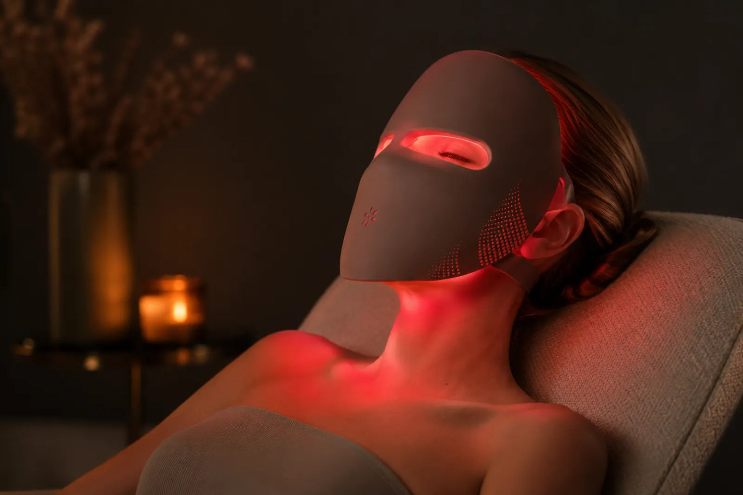 Woman relaxing while wearing a glowing red Lumovex LED light therapy face mask