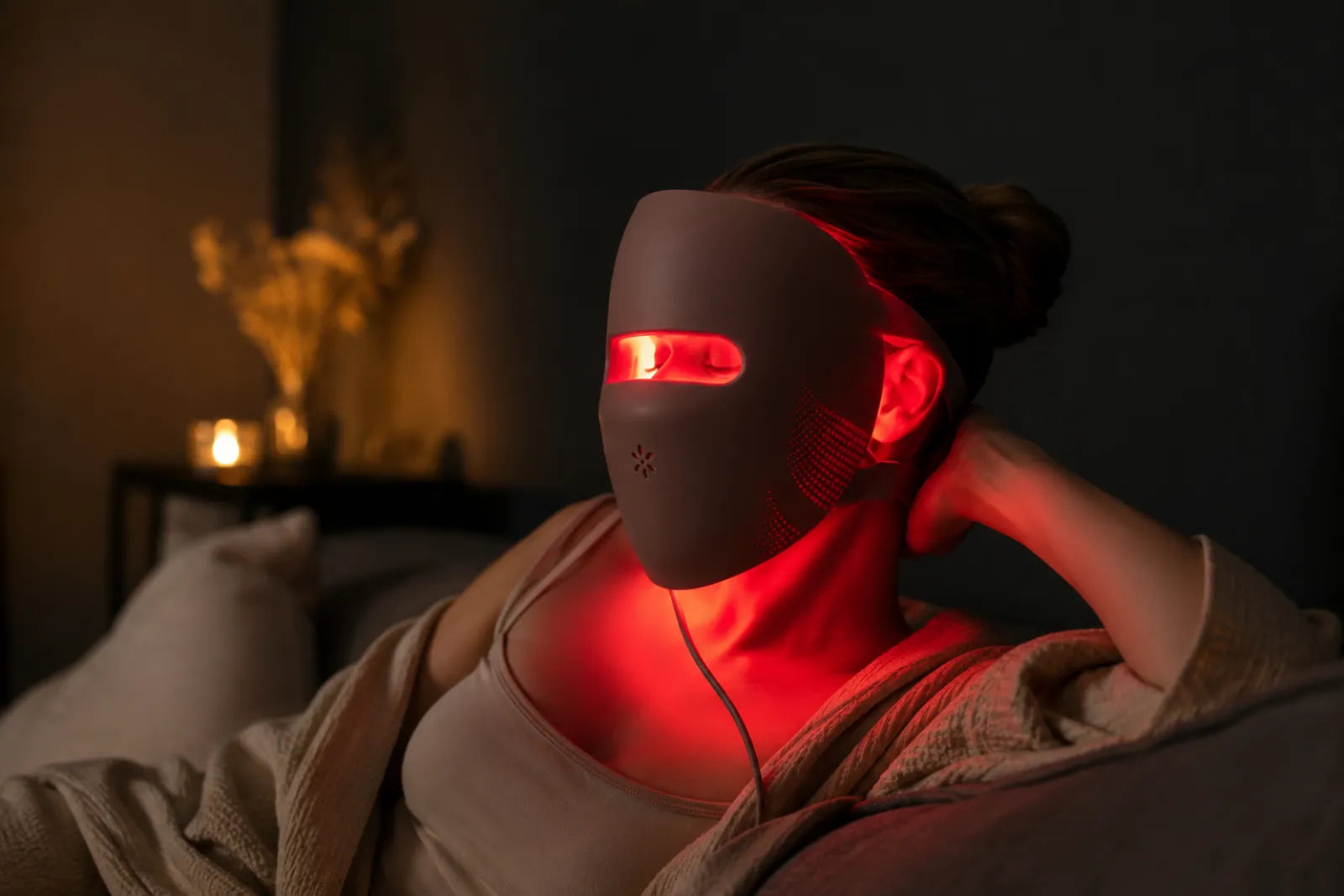 Woman wearing a glowing red Lumovex LED face mask as part of her routine