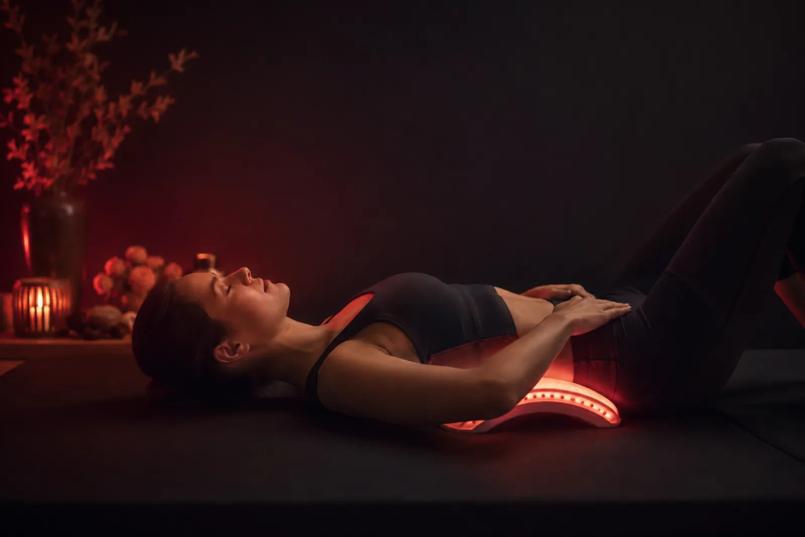 Person easing lower-back tension under soft red light therapy