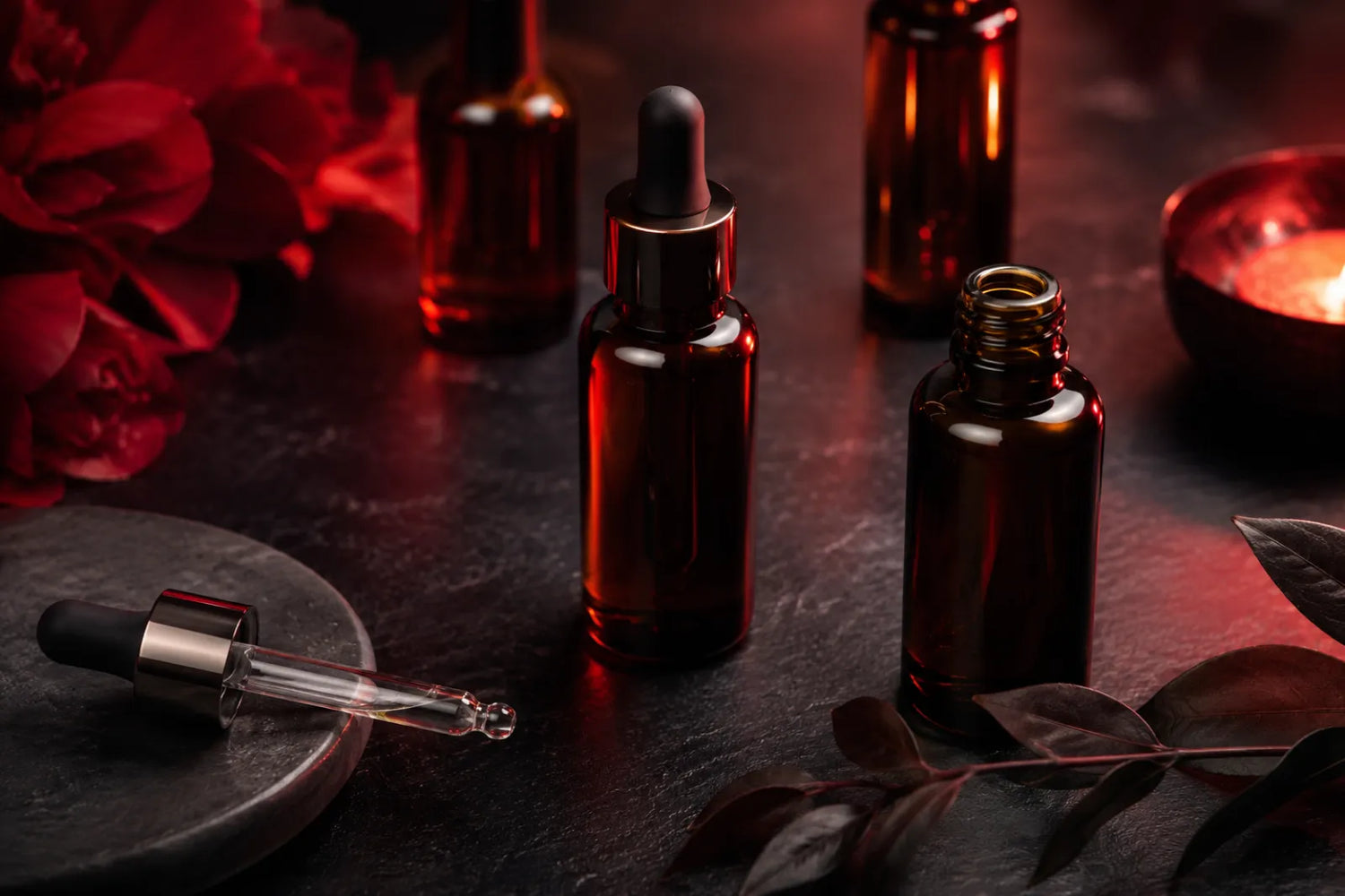 Skincare serums and a dropper under warm red light for use after red light therapy