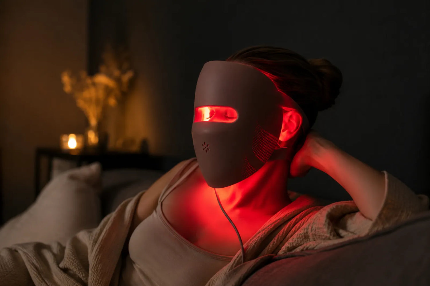 Woman wearing a glowing red Lumovex LED face mask as part of her routine