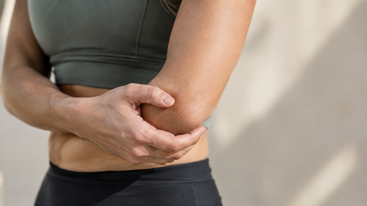 Person cupping the outside of their elbow to ease a dull ache after activity