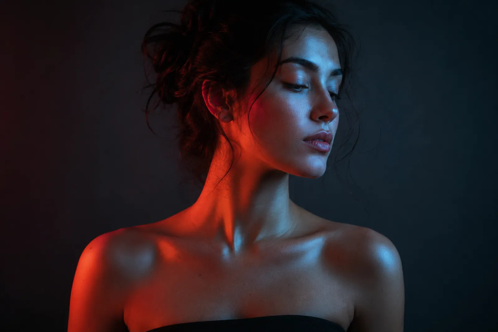 Woman lit with red light on one side and blue light on the other, red versus blue light therapy
