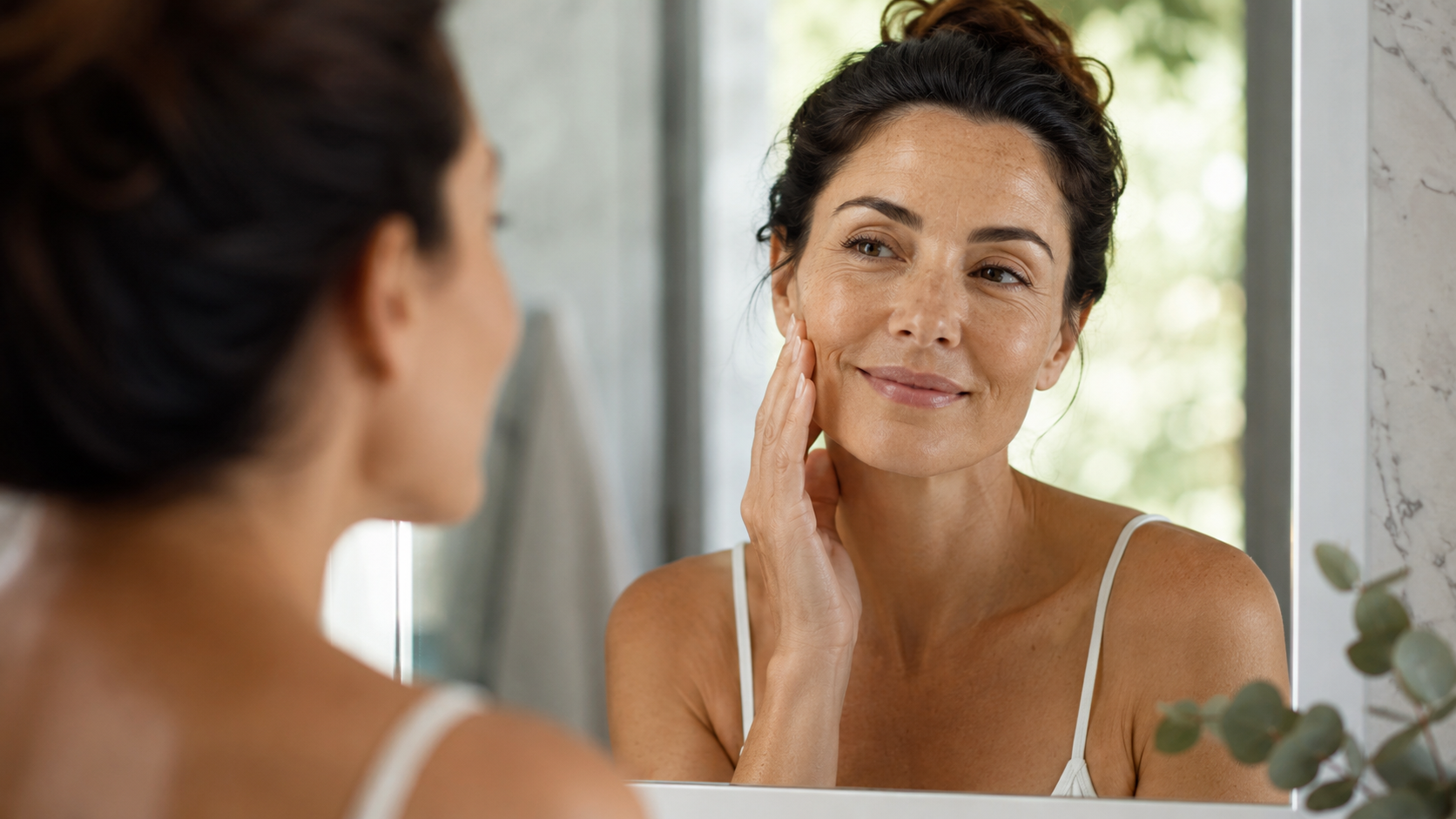 Woman following a consistent skincare routine at the bathroom mirror