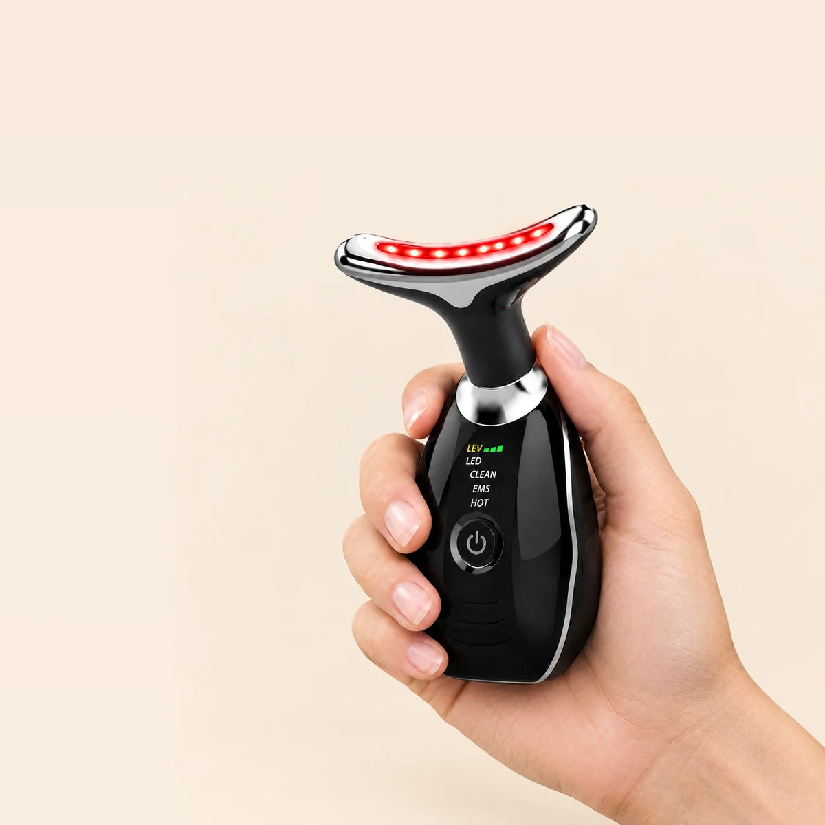 Hand holding the black Lumovex Sculpt Wand, showing its palm-sized rounded body, control labels and curved red LED head