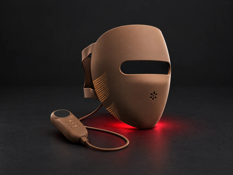 Lumovex Spectrum Pro LED face mask in warm brown silicone with its open visor and brown controller, shown on a dark surface